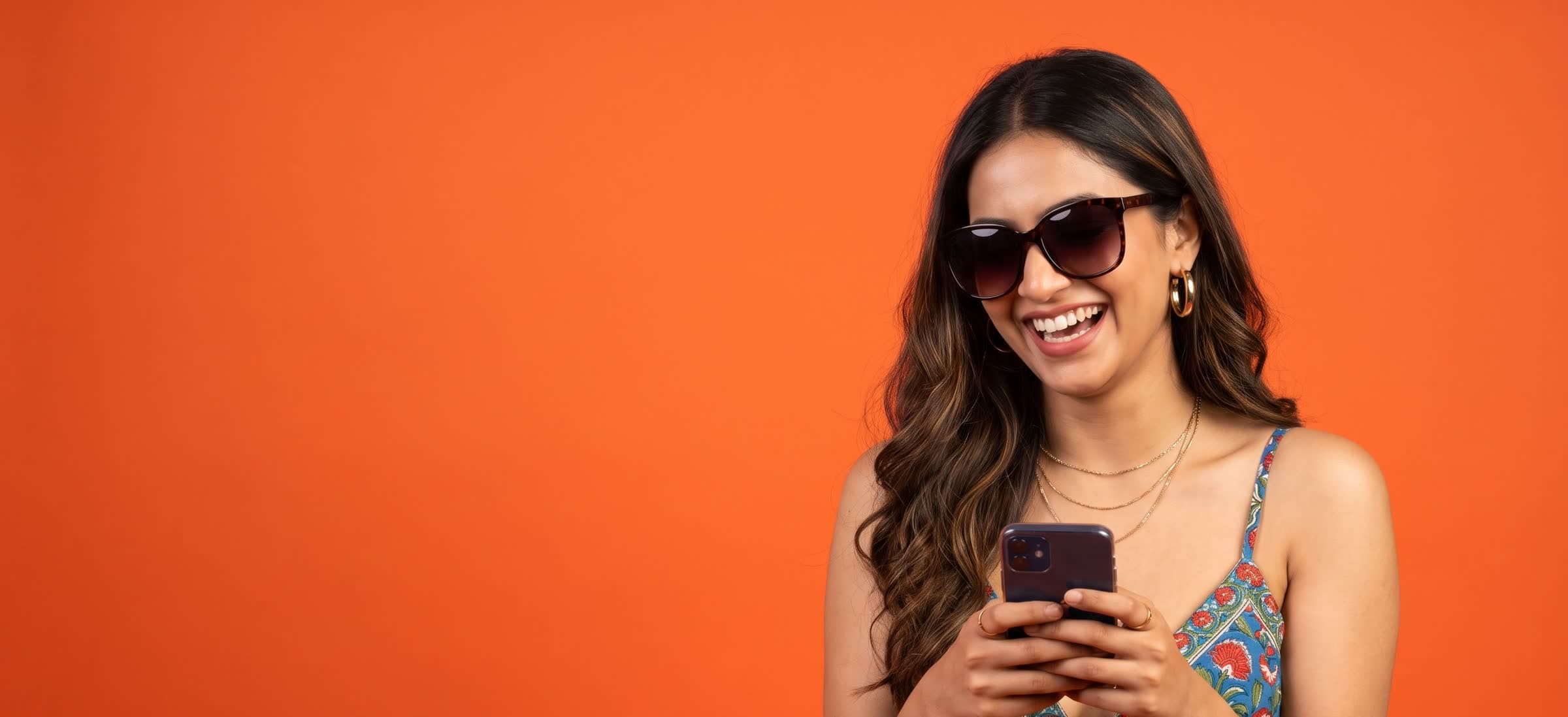 A creator in sunglasses laughing at a message on her phone