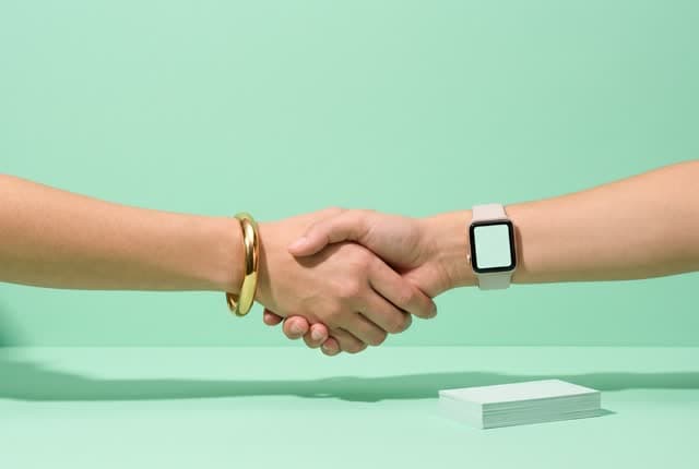 Two people shaking hands next to business cards